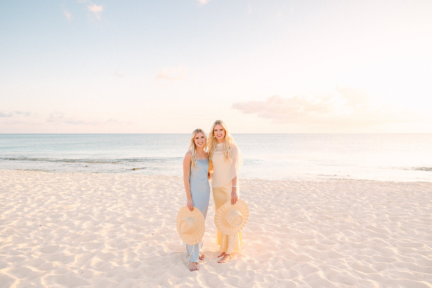 The Southern Stitchers co-founders Casey and Courtney showcasing sun hats on Seven Mile Beach in Grand Cayman, inspiring The Caribbean Collection