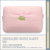 Pink waffle-textured makeup bag with green crocodile logo and 'Snappy Traveler' text on a white background.