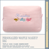 Pink waffle texture makeup bag with embroidered design and text on a white background