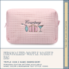Pink waffle-textured makeup bag with embroidered design and text on a white background